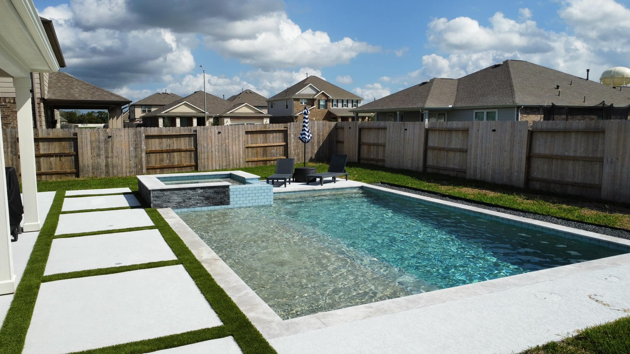 Rectangular custom gunite pool with attached spa and travertine decking