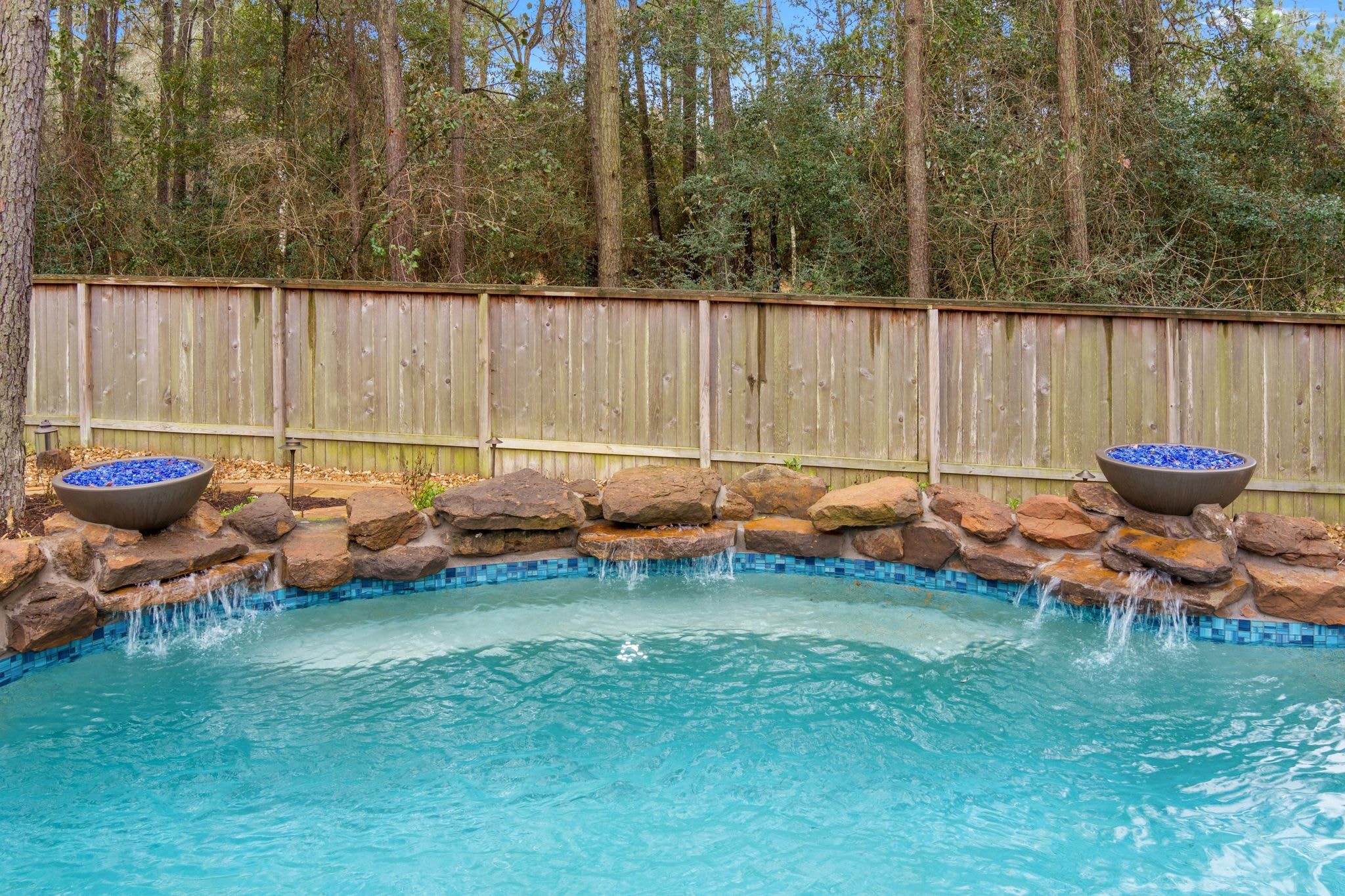 Freeform gunite pool with travertine decking, weeping wall, fire bowls, and fire pit