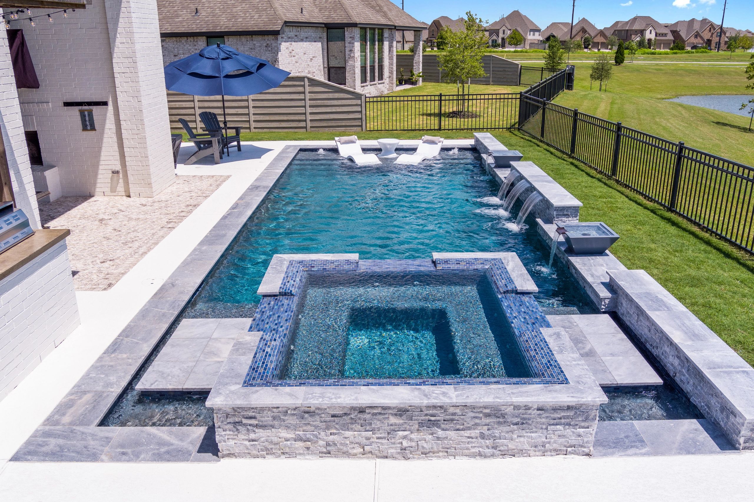 Modern rectangular pool alongside white brick home